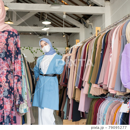 A woman in a veil wearing a mask in blue with present hands something gesture 79095277