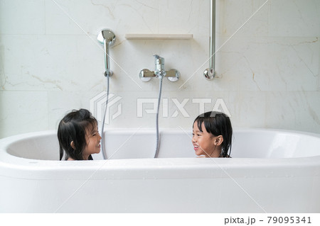 two happy girl taking a bath together on a bathtub 79095341