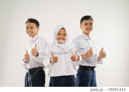 three smiling teenagers wearing junior high school uniforms stand with thumbs up 79095343