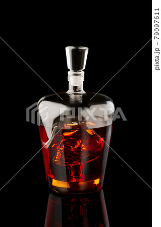 A glass whiskey or rum decanter with scull on dark background A glass whiskey or rum decanter with scull on dark background 79097611