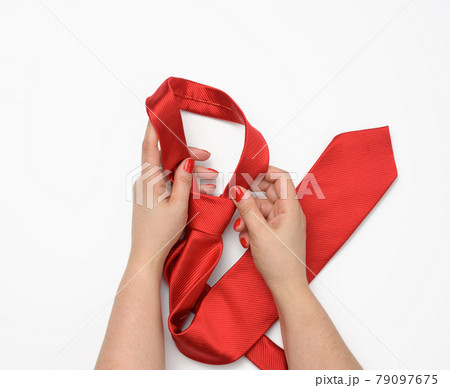two female hands hold a red silk tie on a white background 79097675