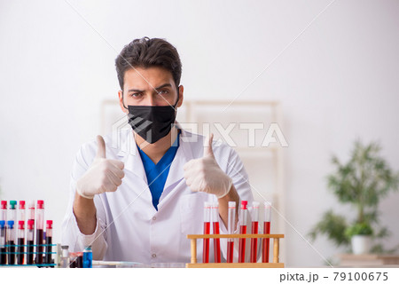 Young male biochemist testing blood samples in pandemic concept 79100675