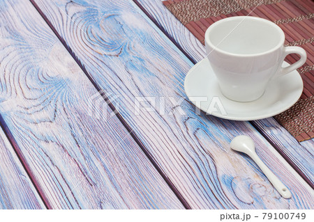 Porcelain cup with saucer and bamboo napkin on wooden background. 79100749