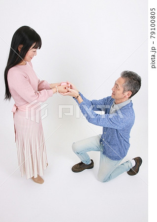 指輪をプレゼントしてプロポーズする男性と受ける女性の写真素材