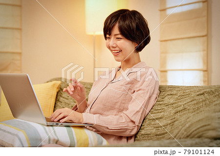 ソファでパソコンを使用する若い女性 79101124