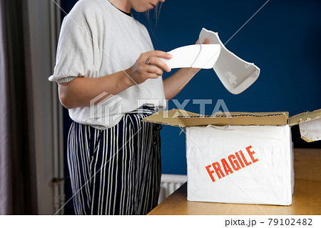 Young woman opening damaged delivery package,online shopping package. Broken fragile plate at home 79102482