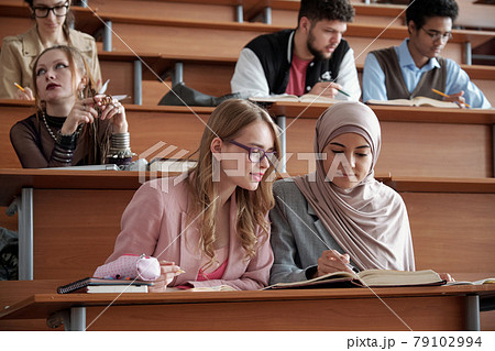 Group of young students sitting by desks at lesson 79102994