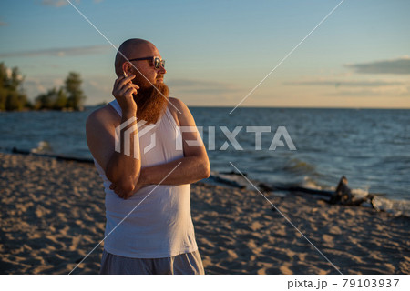 Brutal bearded man smokes a cigarette on the beach. Bad habit leads to cancer Brutal bearded man smokes a cigarette on the beach. Bad habit leads to cancer 79103937