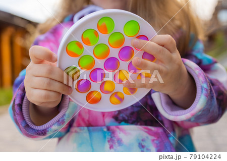 Pop it fidget toy in girl hand's. Colorful antistress kid's toy fidget. Pop it fidget toy in girl hand's. Colorful antistress kid's toy fidget. 79104224