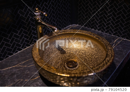 Vintage Beautiful faucet and golden mixer tap on a marble round sink in the bathroom. Interior of an expensive toilet with a marble sink. Vintage Beautiful faucet and golden mixer tap on a marble round sink in the bathroom. Interior of an expensive toilet with a marble sink. 79104520