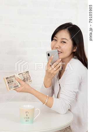 スマホ情報で大金を手に入れ札束を握る若い女性 79105905