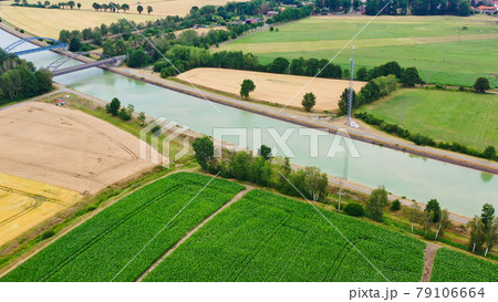 Aerial view of a canal that runs through fields, meadows and arable land in the flat landscape of northern Germany. 79106664