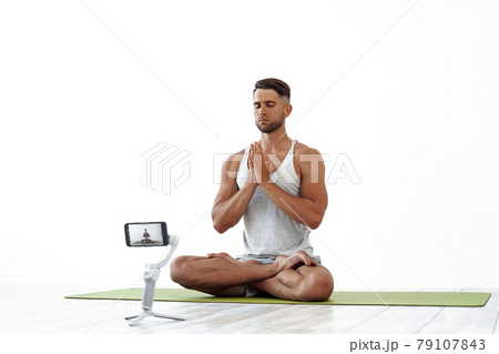 Fit Caucasian male recording a blog or streaming yoga workout. Fit Caucasian male recording a blog or streaming yoga workout. 79107843
