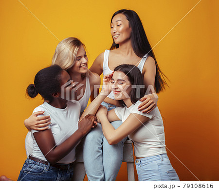 diverse multi nation girls group, teenage friends company cheerful having fun, happy smiling, cute posing on yellow background, lifestyle people concept, african-american, asian and caucasian 79108616
