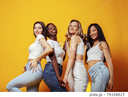 diverse multi nation girls group, teenage friends company cheerful having fun, happy smiling, cute posing on yellow background, lifestyle people concept, african-american, asian and caucasian 79108625