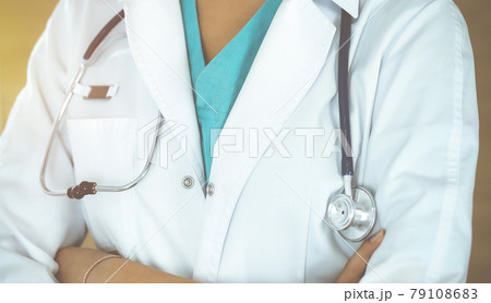 Unknown female doctor standing with arms crossed in sunny clinic, close-up Unknown female doctor standing with arms crossed in sunny clinic, close-up 79108683