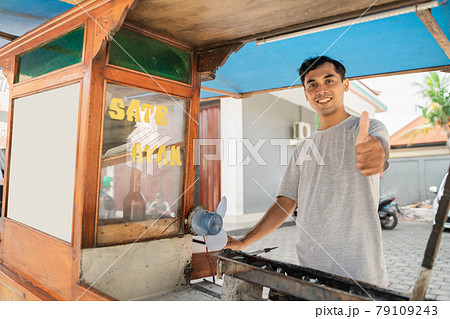 man street food seller of chicken satay with food cart selling sate ayam. 79109243
