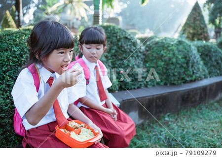 kid primary school student enjoying eating their meal in lunch box 79109279