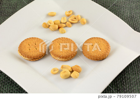 Peanut cream sandwich cookies with peanuts on white snack plate 79109507