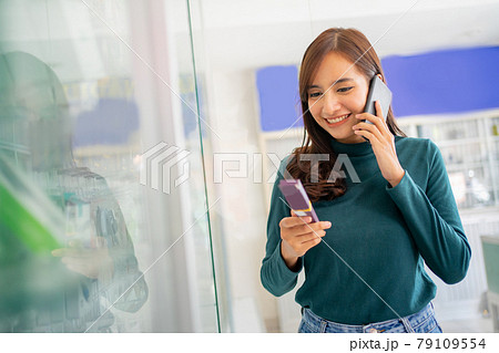 beautiful woman making a call with a smartphone while choosing cell phone accessories 79109554