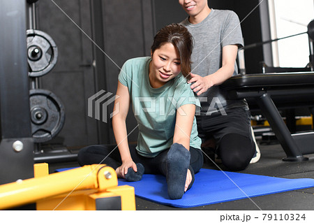 ストレッチするアジア人女性と補助をする男性トレーナー ストレッチするアジア人女性と補助をする男性トレーナー 79110324