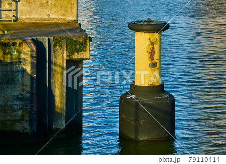 Yellow bollard with black foot in the water of the harbour basin Yellow bollard with black foot in the water of the harbour basin 79110414