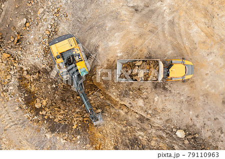 Heavy industrial excavator digs the ground and transfers it to the truck. Heavy industrial excavator digs the ground and transfers it to the truck. 79110963