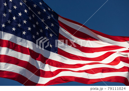 American Flag Waving In Wind Against a Deep Blue Sky. 79111024