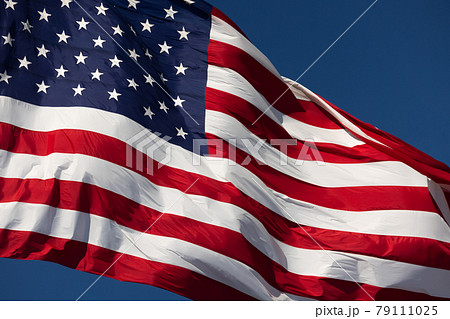 American Flag Waving In Wind Against a Deep Blue Sky. 79111025