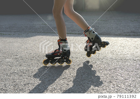 teenager girl's legs wearing roller skates. partial view. teen girl rollerblading in the street. leisure and summer activity teenager girl's legs wearing roller skates. partial view. teen girl rollerblading in the street. leisure and summer activity 79111392