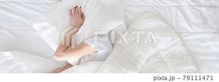 Woman under covers covered her head with pillow top view Woman under covers covered her head with pillow top view 79111471