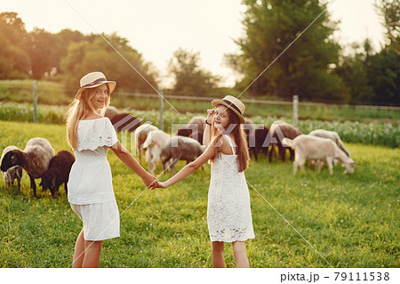 Two cute girls in a field with a goats 79111538