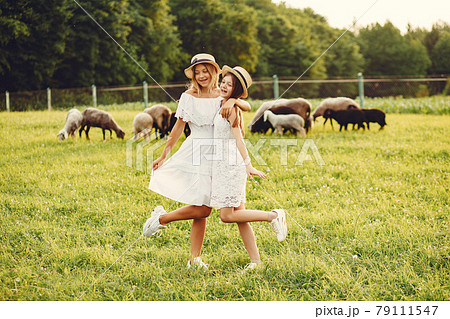 Two cute girls in a field with a goats 79111547