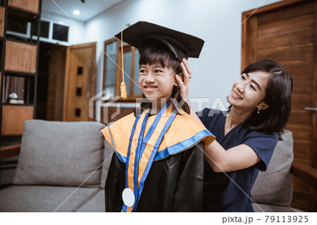 Asian mother and kid preparing on her kinder graduate day at home Asian mother and kid preparing on her kinder graduate day at home 79113925