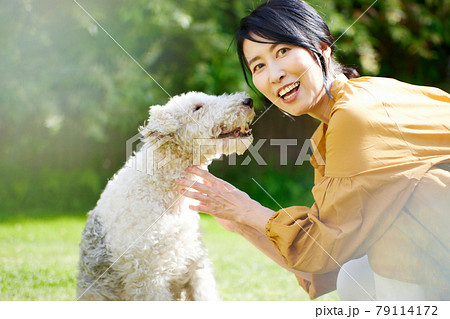 庭で愛犬と戯れるミドル女性 庭で愛犬と戯れるミドル女性 79114172