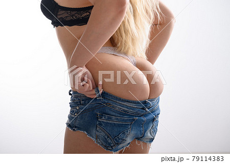 Blonde with long hair puts on denim shorts. A - Stock Photo
