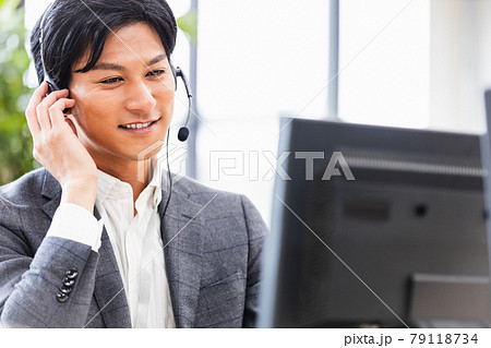 ヘッドセットをつけて耳に手を添えるスーツの男性 79118734