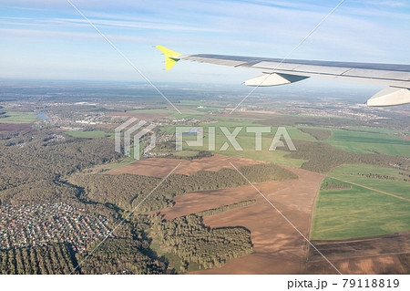 View of airplane wing, blue skies and the land during landing in Moscow, Russia. Airplane window view. View of airplane wing, blue skies and the land during landing in Moscow, Russia. Airplane window view. 79118819