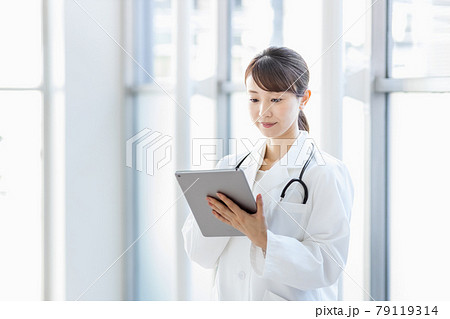 病院内でタブレットPCを持って立つ女性医師 病院内でタブレットPCを持って立つ女性医師 79119314