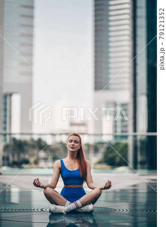 Slim yoga woman in sportswear shorts and top sits Slim yoga woman in sportswear shorts and top sits 79121352