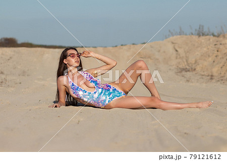 Fit young woman lying on sandy beach on sunny summer day 79121612