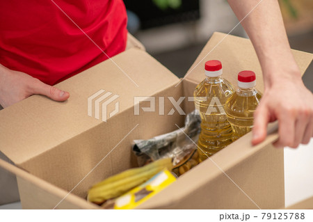 Volunteer hands holding packed open donation box 79125788