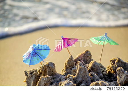 Three small beach umbrellas made of paper for cocktail stand in sand Three small beach umbrellas made of paper for cocktail stand in sand 79133290