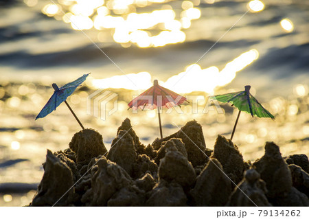 Three small beach umbrellas made of paper for cocktail stand in sand 79134262