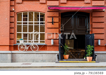 Red brick house facade with window and door and white vintage bicycle. Red brick house facade with window and door and white vintage bicycle. 79136569
