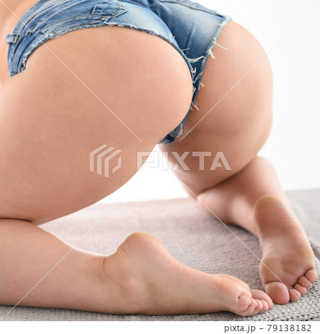 A girl with a big seductive booty sits on a knitted blanket. A