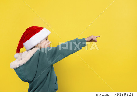 Little beautiful girl in santa hat smiling and pointing her finger. Little beautiful girl in santa hat smiling and pointing her finger. 79139822