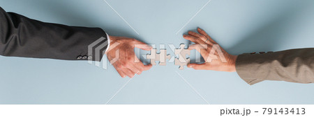 Male and female hand joining two blank matching puzzle pieces 79143413