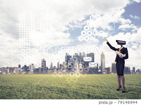 Camera headed woman standing on green grass against modern citys 79146944