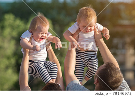 Parents play toss their twin children over their heads 79146972